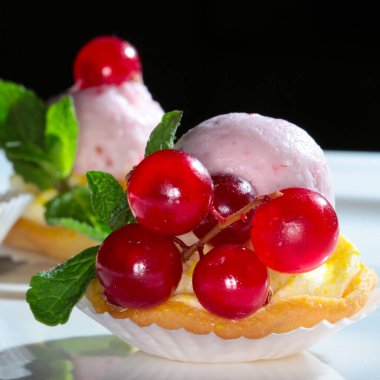 Koyu bir arka plan stüdyosunda kırmızı frenk üzümlü nefis bir pasta.