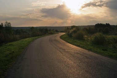 Şafak vakti, sel basmış çayırların ortasında ıssız bir yol boyunca seyahat etmek.