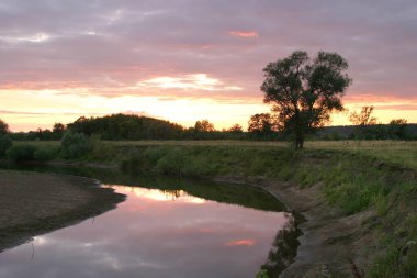 Yazın gün batımında nehirde ve güzel bulutlar suda yansıyor.