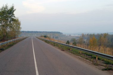 Sonbahar manzarası asfalt yolu sisli bir akşam günbatımında