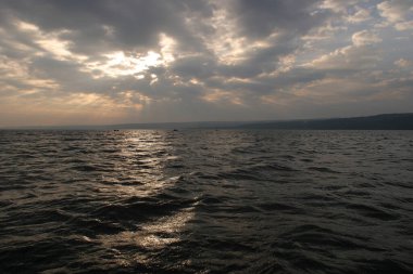 Gün batımında su üzerinde dramatik bulutların manzarası