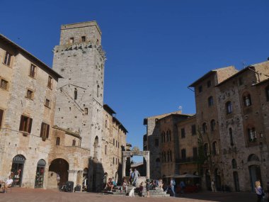 San Gimignano 'daki sarnıç meydanı. Ortasında sekizgen kuyu ve arkasında ortaçağ yüksek kuleleri var.