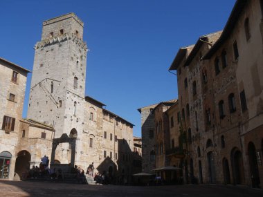 San Gimignano 'daki sarnıç meydanı. Ortasında sekizgen kuyu ve arkasında ortaçağ yüksek kuleleri var.