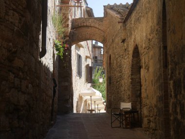Eski binalar boyunca tipik ortaçağ sokağı ve San Gimignano 'nun tarihi merkezinde kaya kemerleriyle kaplı.