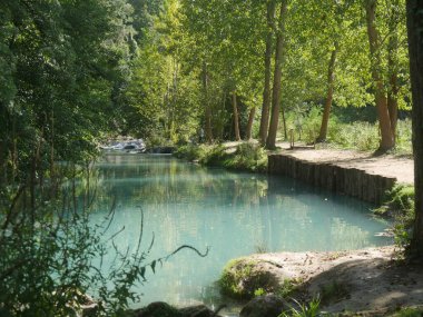 Elsa nehri boyunca uzanan patika, Sentierelsa nehri parkındaki bitki örtüsü arasında kayaya oyulmuş.
