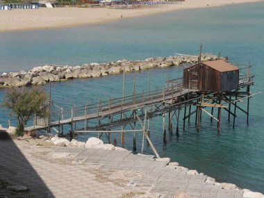 Denizdeki antik balıkçılık makinesi Trabucco şehir duvarları boyunca Termoli 'deki Swabian Kalesi.