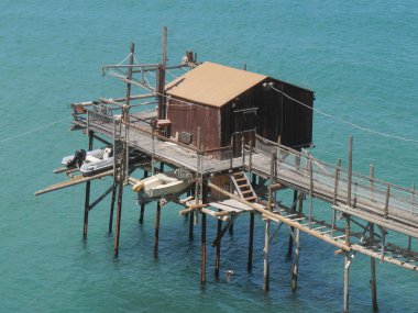 Denizdeki antik balıkçılık makinesi Trabucco şehir duvarları boyunca Termoli 'deki Swabian Kalesi.