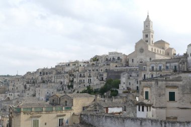 Matera tepesinde beyaz kumtaşı cepheli ve çan kulesi olan bir katedral.