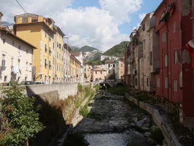 Eski Carrara şehrinin renkli binalarında beyaz çakıl taşlarından oluşan nehir yatağından taşan sel.