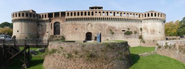 Imola 'daki Sforza Kalesi. Yuvarlak kaleler ve önünde yeşil bir çim olan vadileri olan ana bina.