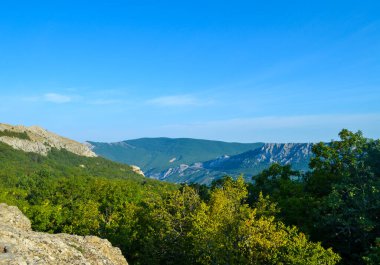 Turistik dağ tırmanışları, uzaktaki dağların gökyüzünün sisinde kaybolmuş ağaçlardan oluşan yeşil bir halı ile kaplı olduğunu gösterdi.