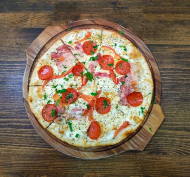 Domates, fesleğen, pepperoni ve jambonlu ev yapımı pizza.