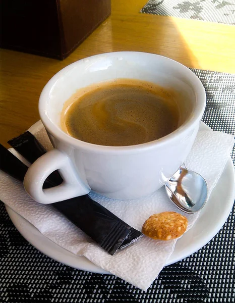 Kopje Koffie Met Schuim Een Witte Schotel Met Zwarte Suikerzakjes — Stockfoto