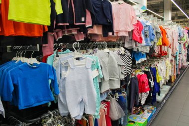 Bir sürü çocuk giysisi perspektifi fotoğrafı bir alışveriş merkezinde satılık elbise sırasına asılmış.