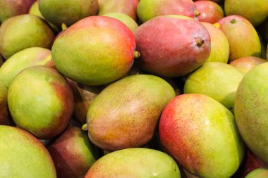 large pile of ripe fresh mango fruits for sale in the supermarket