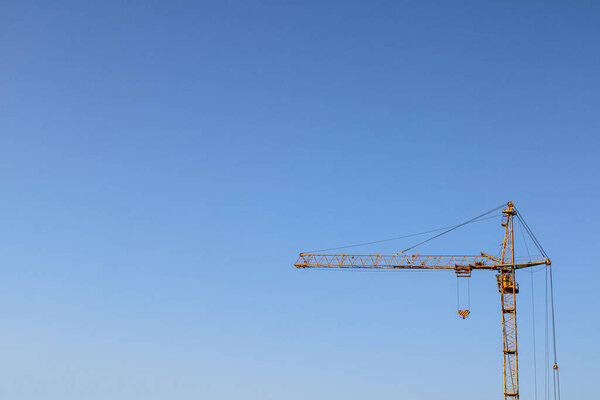 Part of a contrasting yellow construction crane against a large clear sky business background for building architect orders