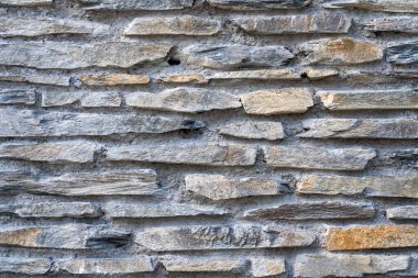 Koyu taş dokusundan yapılmış kaba bir duvar.