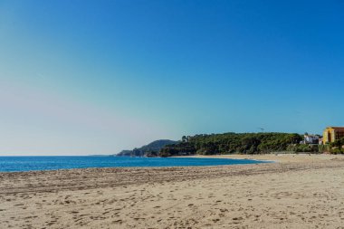 Temiz mavi gökyüzü ve kopyalama alanı olan boş bir sahil manzarası.