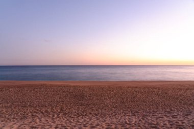 Gün batımında kumlu sahilin uzun pozu, boş plaj. 