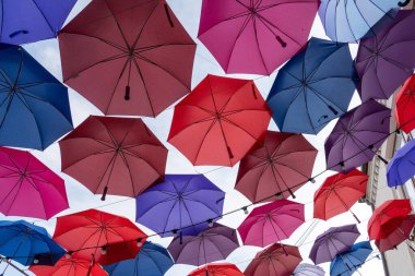 Birçok renkli şemsiye parlak güneşten korunmak için bir kubbe gibi asılır.