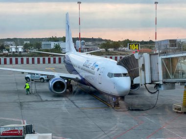 Bucharest, Romania - 05.15.2022: Blue Air plane is parked and ready for loading passengers and luggage, the view from the window of the airport