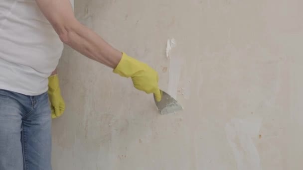 Plasterer man holding putty knife is spackling patching a hole in white wall. — Stok Video