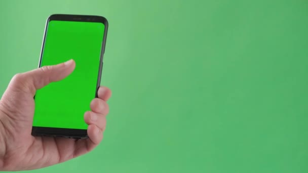 Muž ruka drží smartphone na zelené obrazovce chroma pozadí. — Stock video