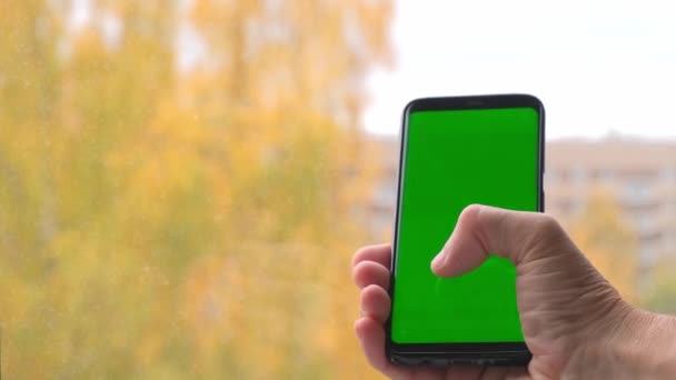 4k. Мужчина держит смартфон с зеленым экраном. — стоковое видео