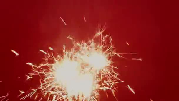 4K. Sparklers Brillante luz de Navidad ardiente sobre fondo rojo. — Vídeo de stock