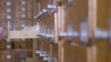4 bin. Kütüphanedeki katalog kartları. Bir adam dosya dolabında bilgi arıyor..