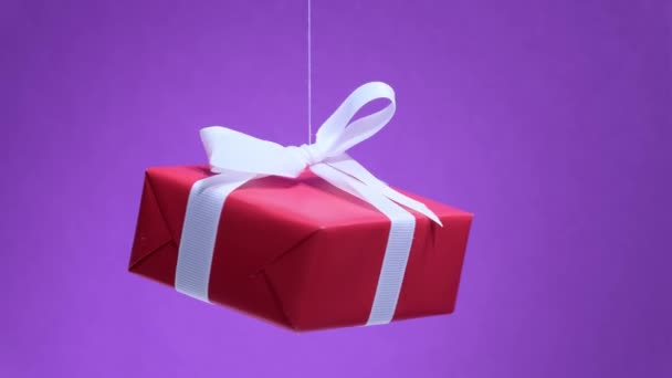Caja de regalo roja con cinta blanca girando en el fondo del color 2022 de moda — Vídeo de stock