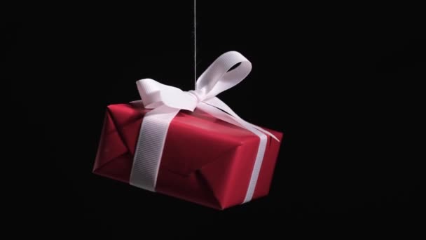 4K. Red gift box with white ribbon spinning on black background. — Stock videók