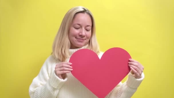 Χαρούμενη νεαρή χαμογελαστή γυναίκα με μια χάρτινη καρδιά στα χέρια της — Αρχείο Βίντεο