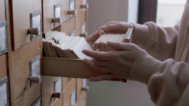 Kütüphanedeki katalog kartları. Kadın dosya dolabında bilgi arıyor.