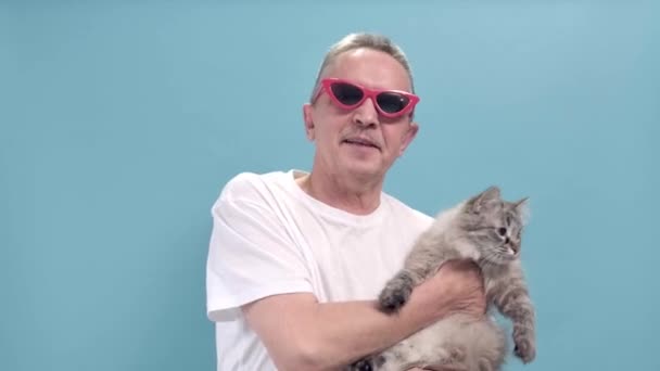4K. Bărbat în vârstă într-un tricou alb ține o pisică în mâini — Videoclip de stoc