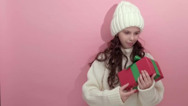 Gelukkig jong meisje draagt witte gebreide trui, sjaal en hoed met geschenkdoos — Stockvideo