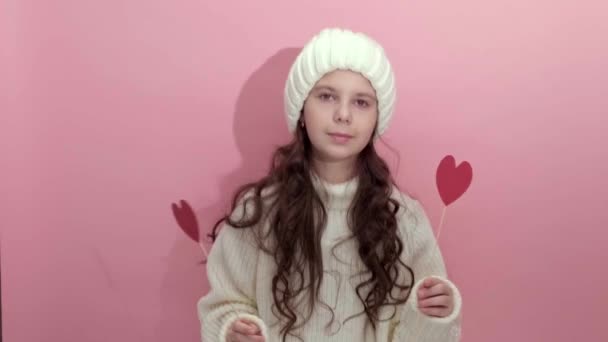 Felice Giovane ragazza indossa maglione bianco maglia tenendo cuori rossi sopra gli occhi — Video Stock