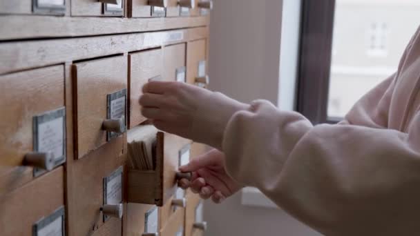 Cartões de catálogo na biblioteca. Feminino está procurando informações em um armário de arquivos — Vídeo de Stock
