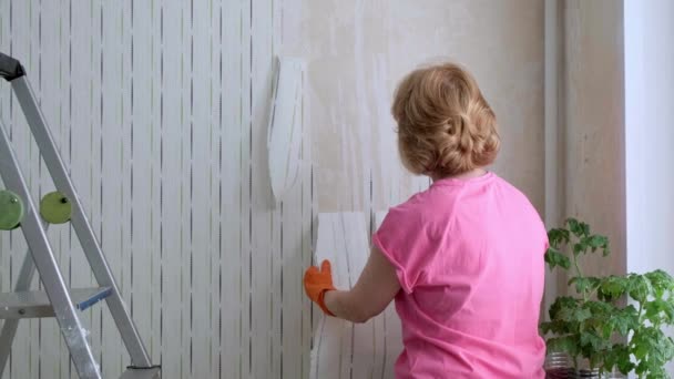 Kvinna att ta bort gamla tapeter från väggar förbereder för platt renovering. — Stockvideo