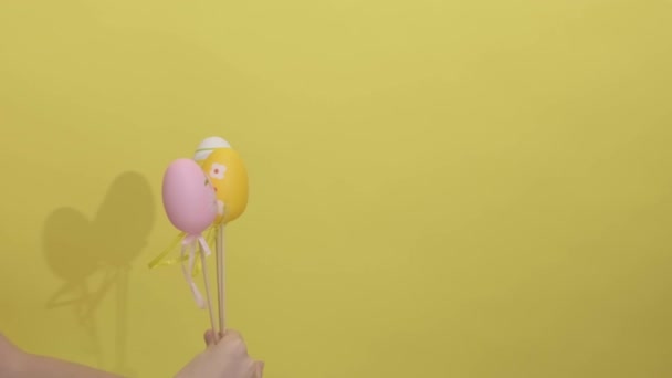 4k. Дві руки дають один одному великодні яйця на жовтому тлі . — стокове відео