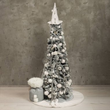 Beton zemin üzerinde izole edilmiş gri-beyaz uzun Noel ağacı 
