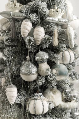 Gri-beyaz Noel ağacının yanında yumuşak oyuncaklar ve çelenkler.