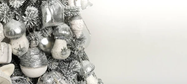 Изолированная серовато-белая елка с игрушками и гирляндами на белом фоне — стоковое фото
