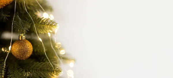 緑黄色のクリスマスツリー上の金のボールのおもちゃとガーランドの閉鎖 — ストック写真