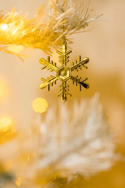 白い黄色のクリスマスツリー上の金の雪の結晶のおもちゃとガーランドの閉鎖 — ストック写真