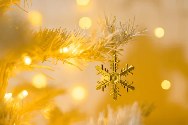 白い黄色のクリスマスツリー上の金の雪の結晶のおもちゃとガーランドの閉鎖 — ストック写真