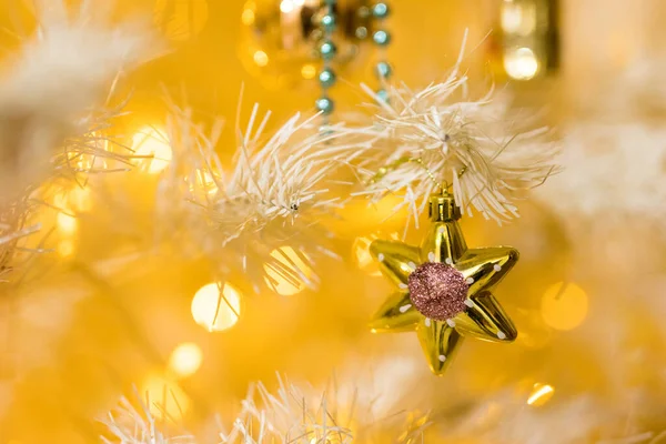 Κοντινό πλάνο του χρυσού αστεριού παιχνίδι και γιρλάντες σε λευκό κίτρινο χριστουγεννιάτικο δέντρο — Φωτογραφία Αρχείου