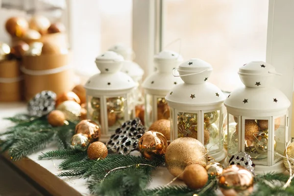 Vista lateral do local de férias com brinquedos de bolas de ouro e castiçais brancos em uma janela — Fotografia de Stock