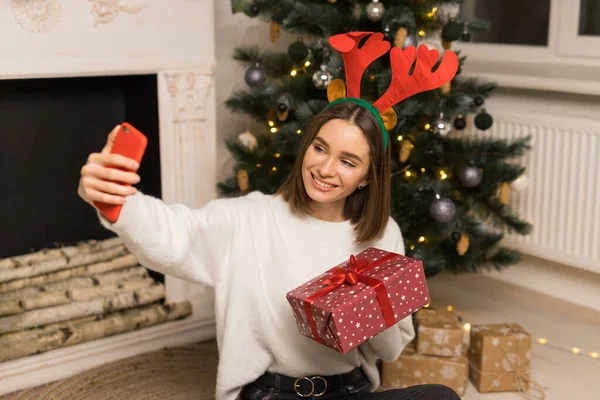 Mladá dívka telefon rodičům a ukázat červený vánoční dárek — Stock fotografie