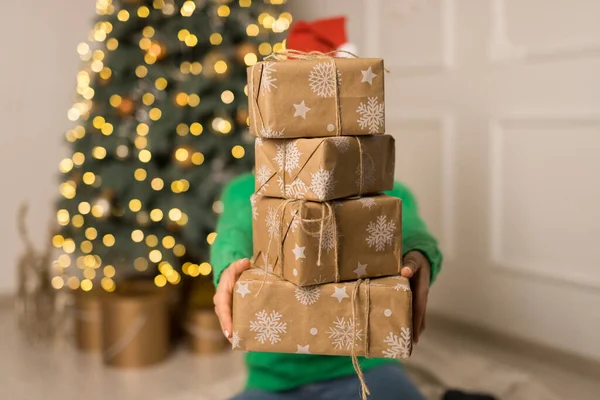 The young girl hold brown gifts near Christmas festive tree — Stock Photo, Image